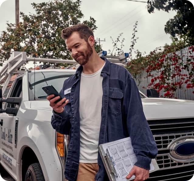 Worker viewing his phone in front of his work truck